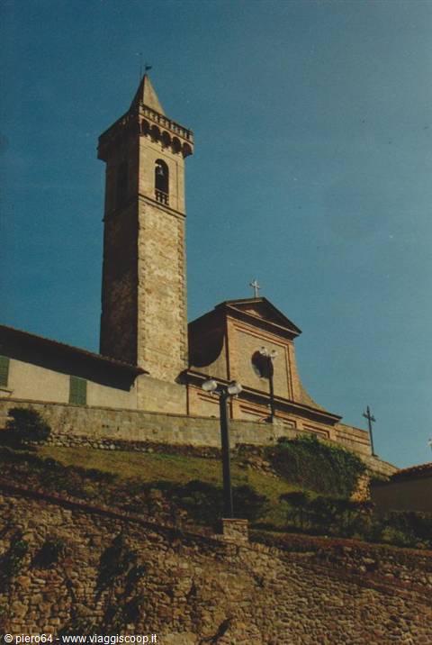 Stone church with tall crenellated bell tower under blue sky