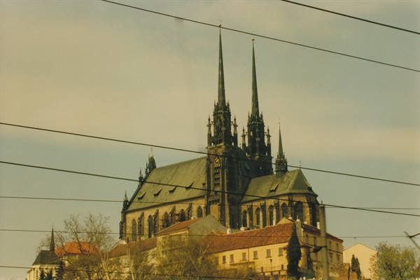 Gothic revival church with twin spires behind power lines and red rooftops