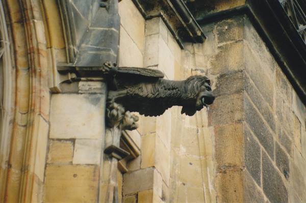 Gothic stone gargoyle protruding from the facade of Prague Cathedral