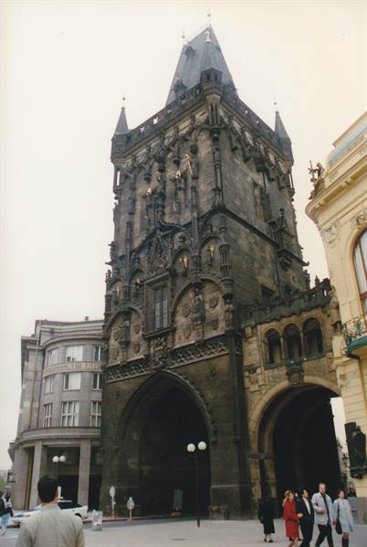 The Powder Tower in Prague, pedestrians pass under the gothic arch on an overcast day