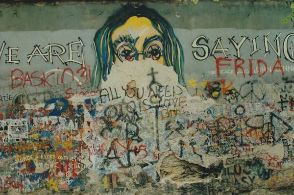 Lennon Wall in Prague: painted portrait and colorful graffiti over weathered plaster