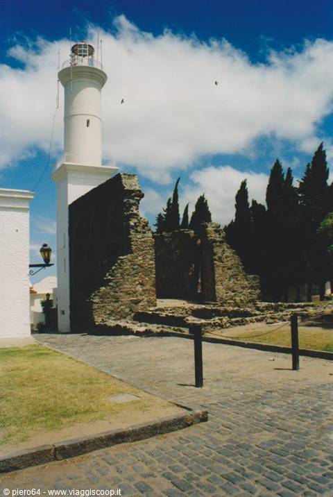 White lighthouse beside ancient stone ruins in Colonia del Sacramento, cloudy sky