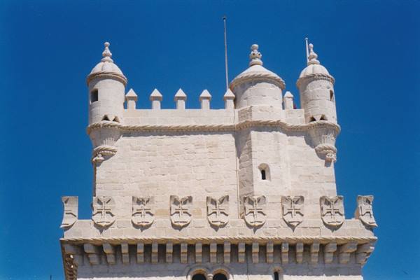 Belém Tower in Lisbon, stone battlements and turrets against a blue sky