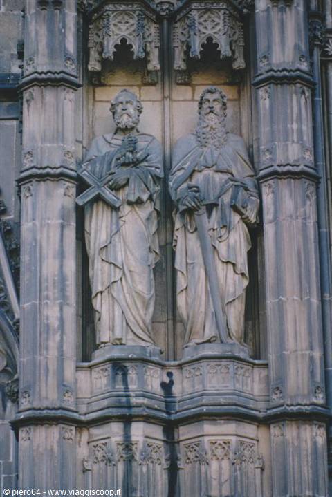 Two stone statues of saints with cross and sword on Cologne Cathedral facade