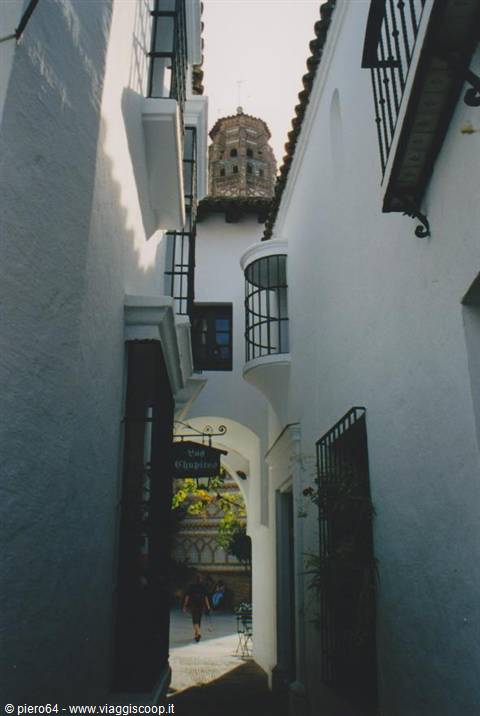 Whitewashed Andalusian alley with wrought-iron balconies and minaret tower