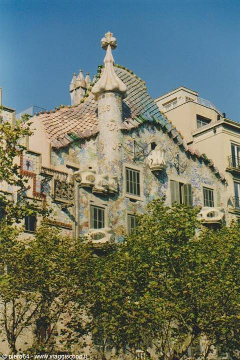 Gaudí's Casa Batlló in Barcelona, trencadís façade behind green trees
