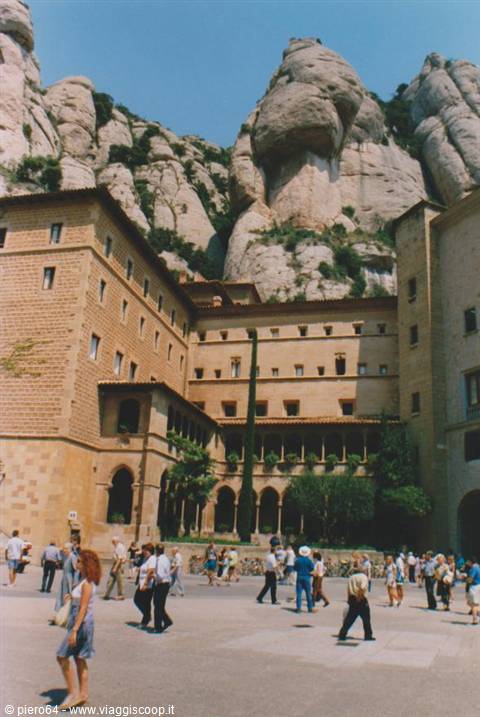 Tourists walk in the square of Montserrat monastery beneath the rocky peaks