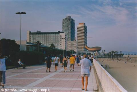 Crowded promenade by the beach, skyscrapers and golden fish sculpture, Barceloneta