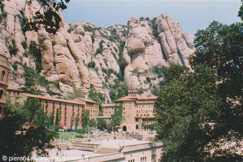 Montserrat monastery nestled beneath jagged rock formations among green trees