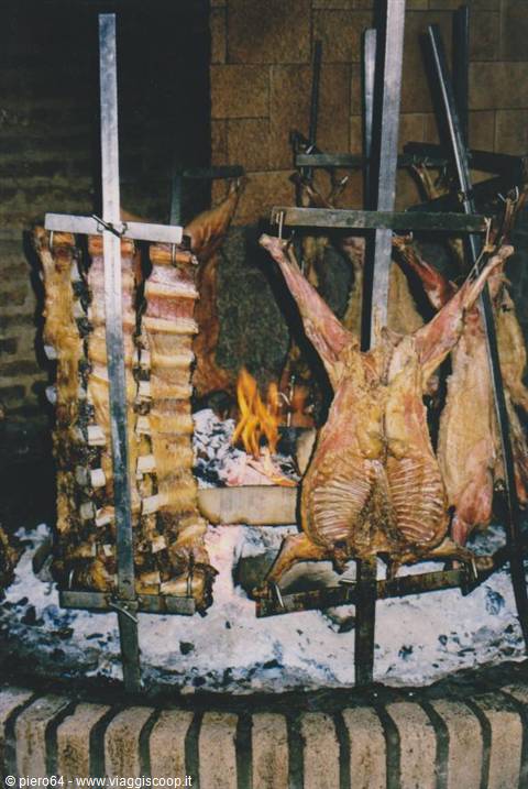 Whole lambs roasted on vertical spits in front of glowing embers