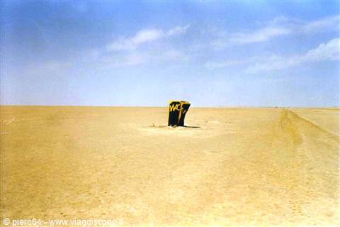  painted metal barrel standing alone on desert sand
