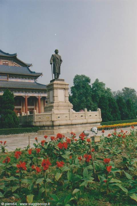 Bronze statue on stone pedestal before the Sun Yat-sen Memorial Hall, red flowers