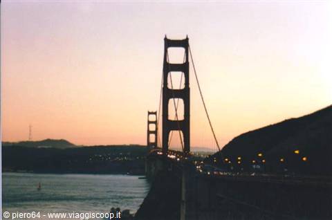 Golden Gate Bridge at dusk, roadway lights glowing against the pink sky