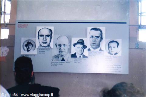 Visitors look at a panel with black-and-white portraits of famous inmates