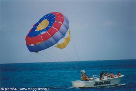 Parasail boat with multicolored canopy towing passengers on turquoise sea