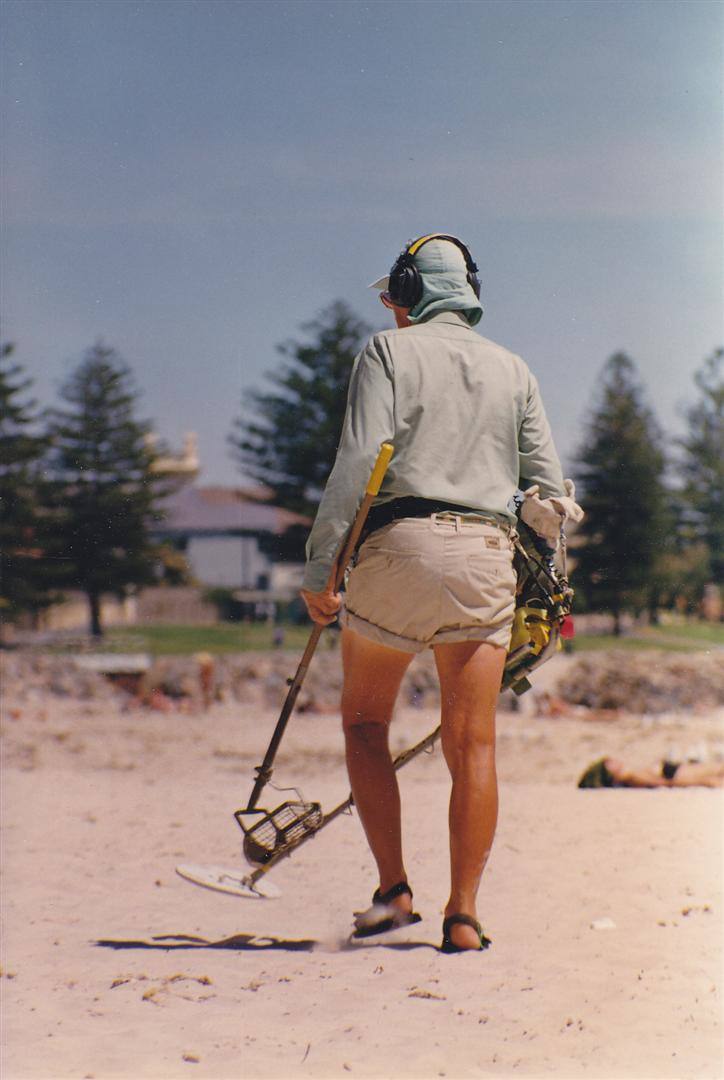 Uomo con cuffie e metal detector cerca tesori sulla sabbia