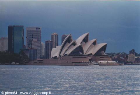 Sydney Opera House with its white sails seen from the sea, skyscrapers behind
