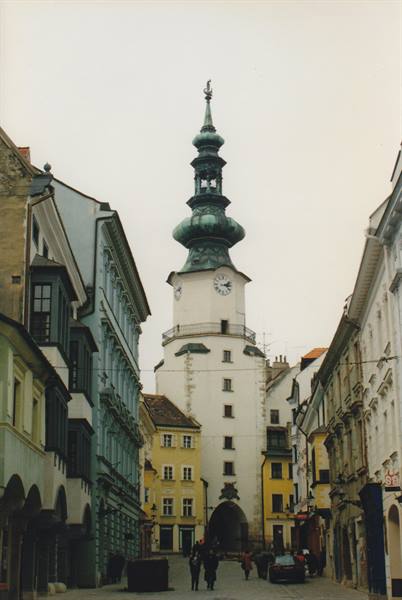St. Michael's Tower in Bratislava, green dome above colorful houses, people walking