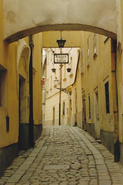 Cobblestone uphill lane between yellow houses, Ratskeller sign beneath the arch