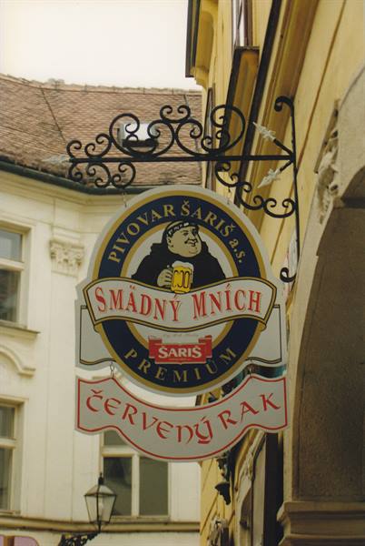 Beer sign with monk on wrought-iron bracket outside a yellow building