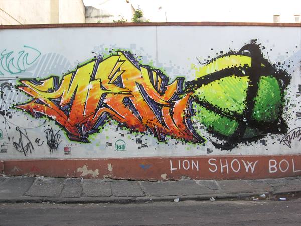 Orange and green graffiti on white wall reading LION SHOW BOL