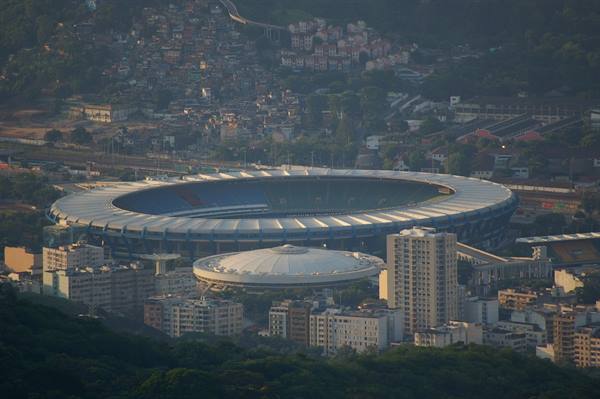 The Maracanã stadium surrounded by buildings, with favela houses on the green hill