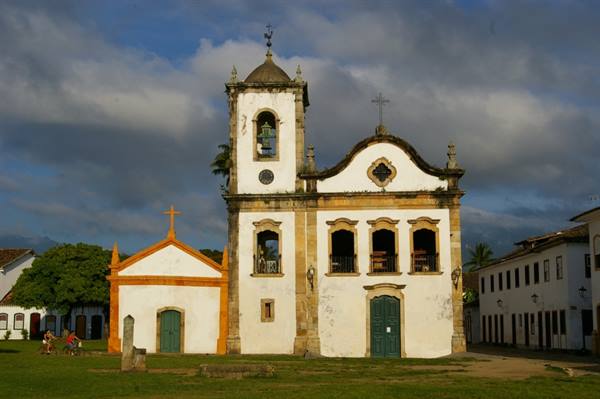 White colonial church with bell tower and orange chapel in Paraty