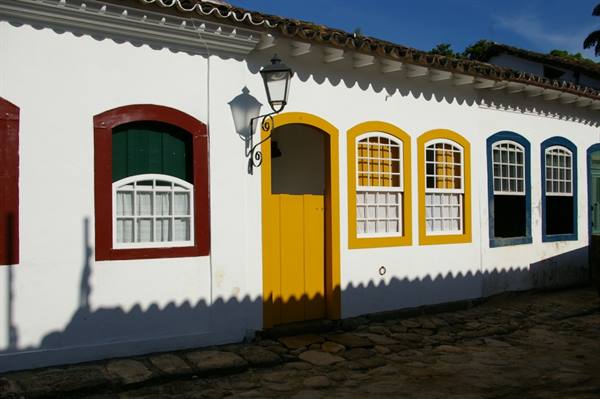 White colonial house with colorful doors and windows, black lantern, cobblestone street