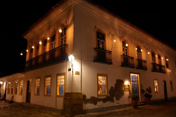 White colonial building lit at night, wrought-iron balconies, glowing lanterns