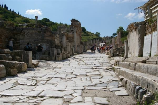 Tourists walk along the marble-paved street among the ruins of Ephesus