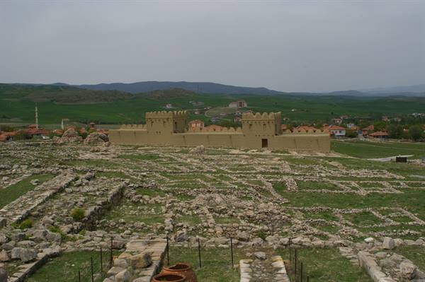 Reconstructed walls of Hattusa above excavated ruins, green hills and grey sky