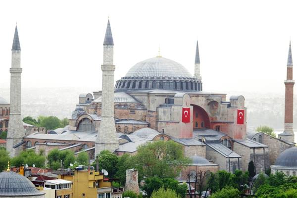 Hagia Sophia in Istanbul, dome and minarets with Turkish flags and trees