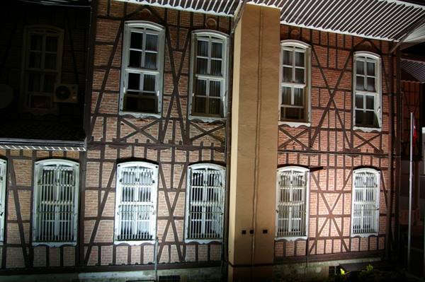Brick and timber-framed facade with barred windows lit at night