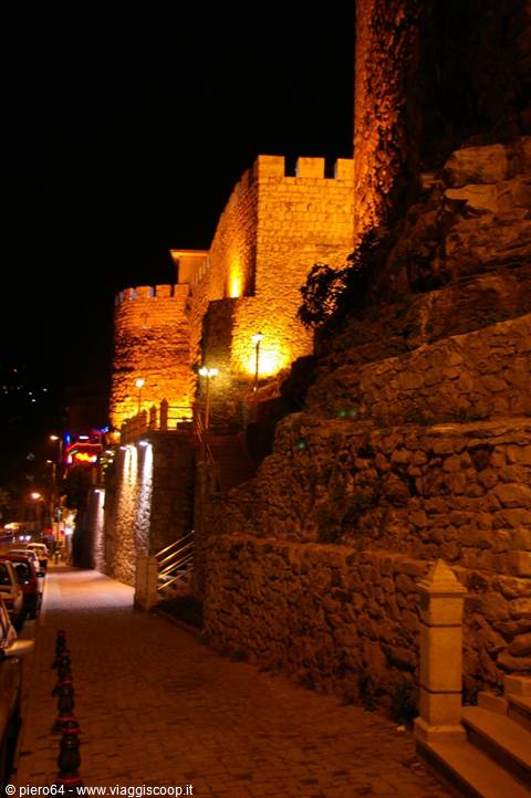 Alanya castle walls lit up at night above the cobbled street