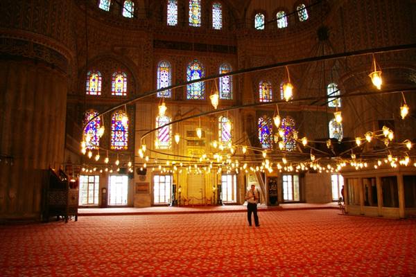Inside Istanbul's Blue Mosque, hanging lamps and vast red carpet