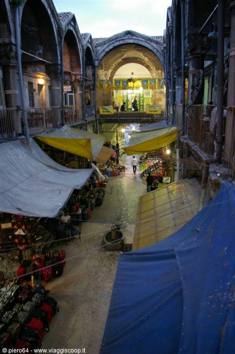 Covered bazaar with stone arches and colorful tarps over market stalls