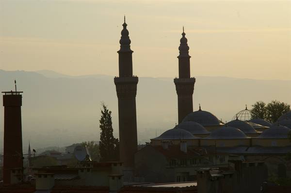 Mosque minarets and domes silhouetted over the hazy city, Bursa