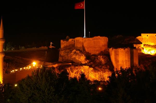 Turkish flag over illuminated ancient walls at night, minaret on the left