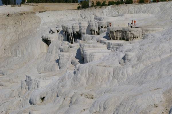 Visitors walk on the white travertine terraces of Pamukkale