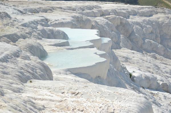 White travertine terraces with turquoise pools at Pamukkale, bright sunlight