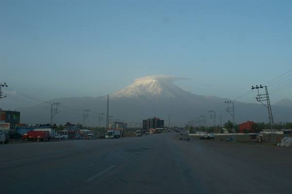 Road with trucks toward snow-capped Mount Ararat under pale morning light