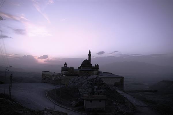 Ishak Pasha Palace with mosque and minaret on rocky hill, purple dawn light