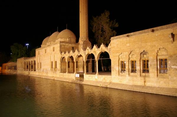 Balıklıgöl in Urfa: stone mosque with domes and arcade lit at night beside the water