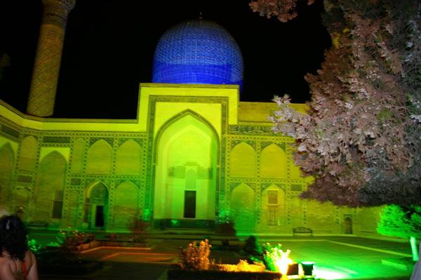 Madrasa lit green at night with blue dome in Samarkand