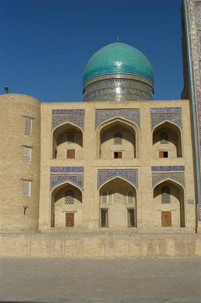 Madrasa in Bukhara, turquoise tiled dome above brick arches