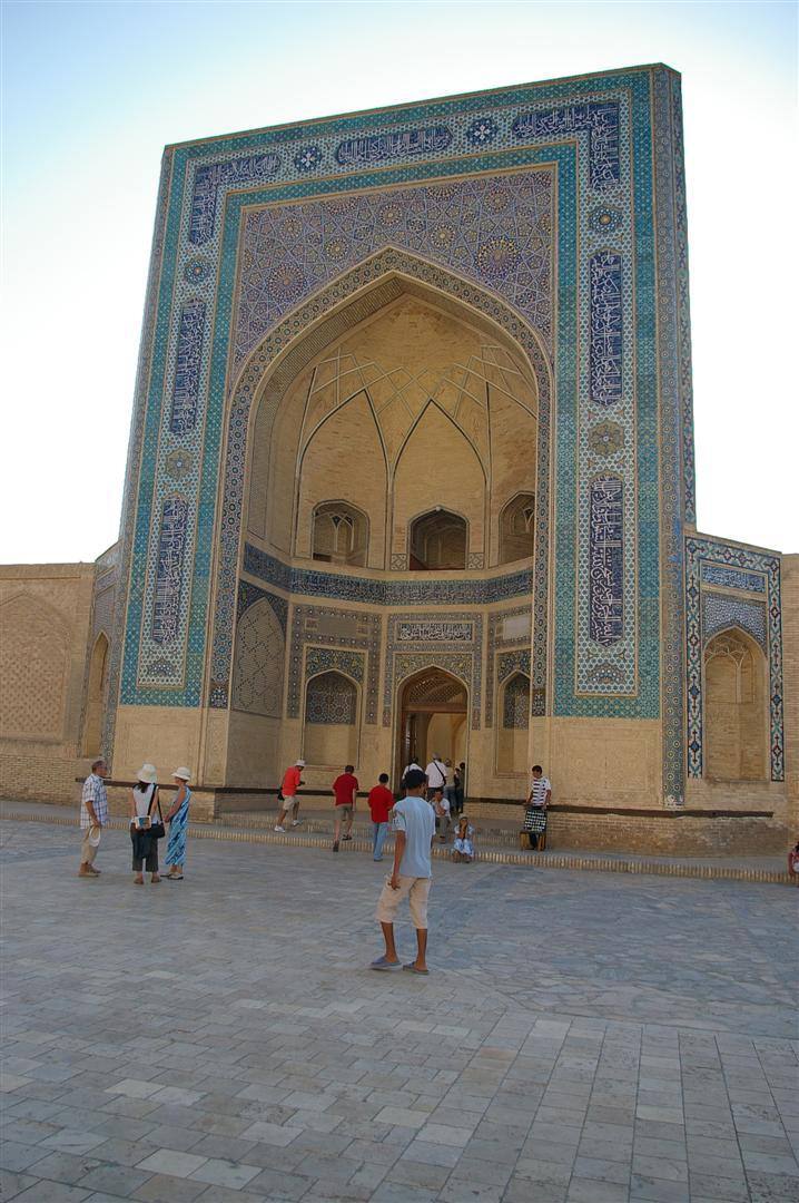 Turisti davanti al portale in mattoni e maioliche blu della madrasa di Bukhara