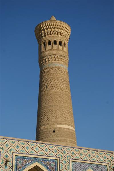 Kalyan minaret with brick patterns above blue tiled arches, Bukhara