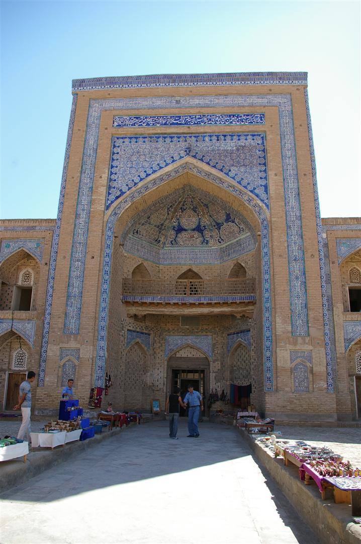 Turisti davanti a un mausoleo antico decorato con piastrelle azzurre, luce solare intensa