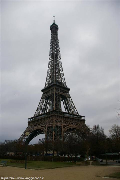 The Eiffel Tower wrought-iron lattice under a grey sky, from Champ de Mars