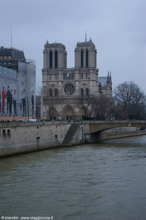 Notre-Dame Cathedral by the Seine, grey sky, stone bridge